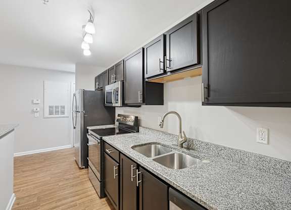 A kitchen with black cabinets and a granite countertop.