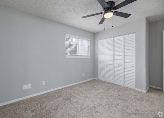 A room with a ceiling fan and carpeted floor.