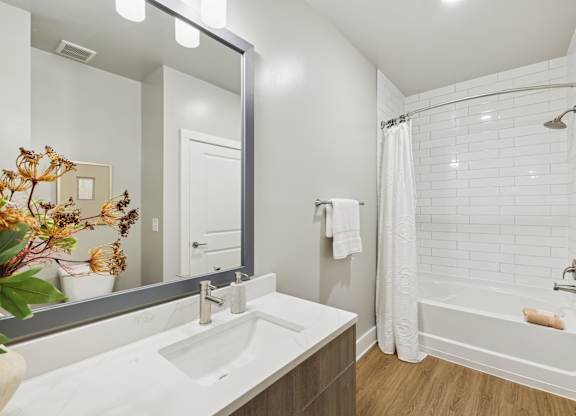 A white sink in a bathroom with a white tub and a white shower curtain at The Beacon at 331 Apartments, Santa Rosa Beach, FL