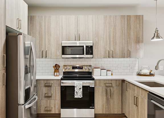A modern kitchen with wooden cabinets and stainless steel appliances at The Beacon at 331 Apartments, Santa Rosa Beach, FL