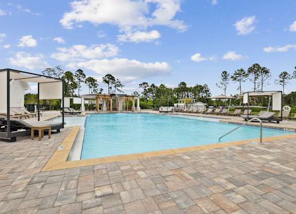 A large outdoor swimming pool surrounded by lounge chairs and umbrellas at The Beacon at 331 Apartments, Santa Rosa Beach, FL