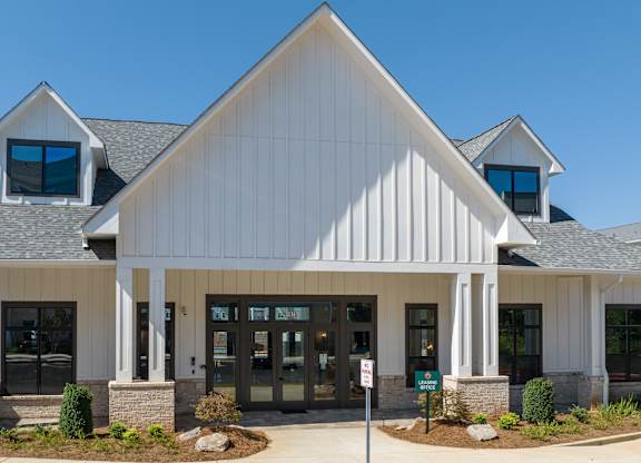 A white building with a black roof and a sign in front at The Ashton at East Park Apartments, Kennesaw, GA, 30144