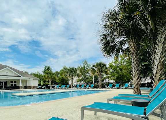 A pool with blue loungers and a building in the background.
