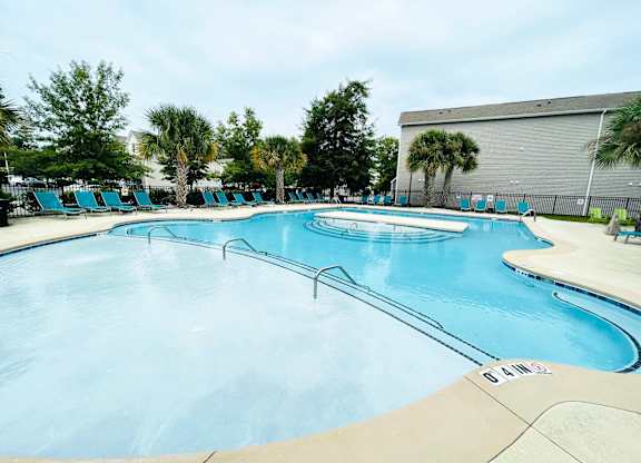 A large outdoor swimming pool with a concrete edge and no people in it.
