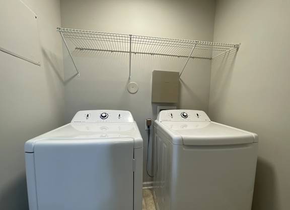 Two white washing machines in a small laundry room.