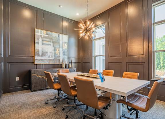 A conference room with a long table and chairs at The Ashton at East Park Apartments, Kennesaw, GA