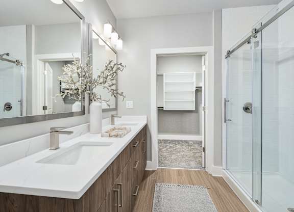 A bathroom with a white sink and a glass shower at The Ashton at East Park Apartments, Kennesaw, Georgia