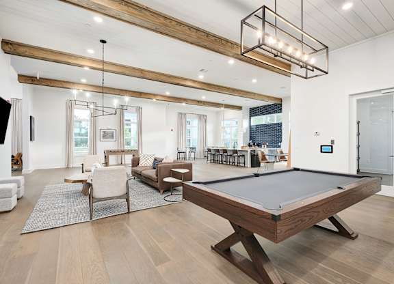 A billiard table is in the middle of a room with a white couch and a TV.