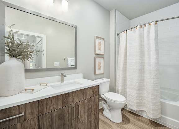 A bathroom with a white sink, toilet, and shower curtain at The Ashton at East Park Apartments, Georgia