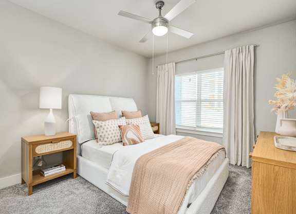 A bedroom with a bed, nightstand, and a ceiling fan at The Ashton at East Park Apartments, Kennesaw, GA, 30144