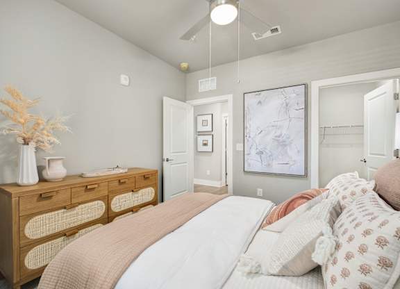 A bedroom with a bed, dresser, and a painting on the wall at The Ashton at East Park Apartments, Kennesaw