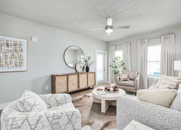 A living room with a white couch, a wooden cabinet, and a painting on the wall at The Ashton at East Park Apartments, Kennesaw, 30144