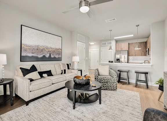 A living room with a large painting on the wall and a white couch at The Ashton at East Park Apartments, Georgia