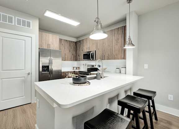 A kitchen with a white countertop and black stools at The Ashton at East Park Apartments, Kennesaw, GA, 30144