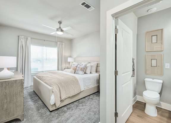 A bedroom with a bed, a toilet, and a mirror at The Ashton at East Park Apartments, Kennesaw, Georgia