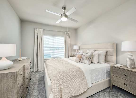 A bedroom with a large bed, two nightstands, and a ceiling fan at The Ashton at East Park Apartments, Georgia, 30144