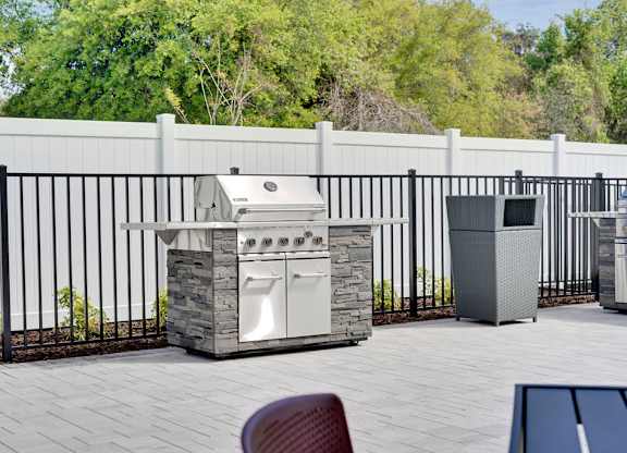 A white outdoor kitchen with a grill and sink.