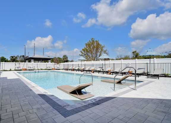 A pool with a bench and a tree in the background.