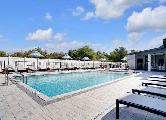 A large outdoor swimming pool with sun loungers and umbrellas.