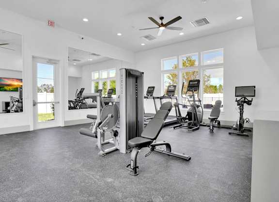 A gym with a variety of equipment including a squat rack, bench press, and a rowing machine.
