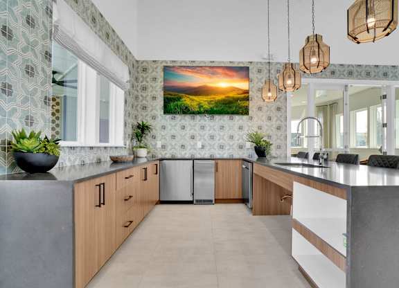 A kitchen with a large painting of a sunset on the wall.