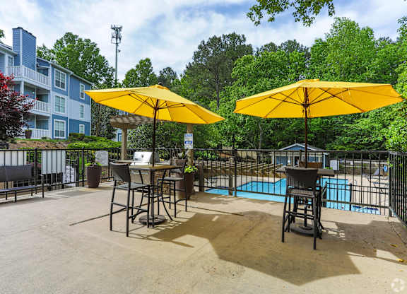 A pool area with two yellow umbrellas and a table.