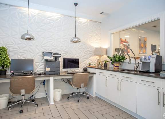 A white kitchen with a desk and chairs.