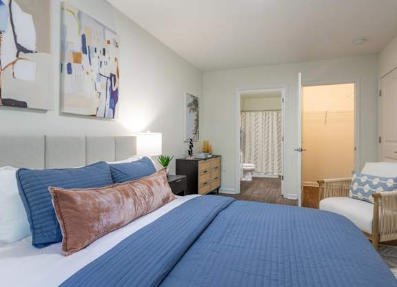 A bedroom with a large bed and a chair.