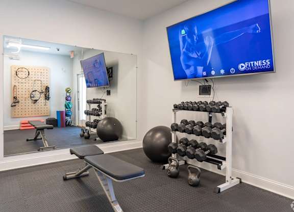 A gym room with a television screen showing a fitness program.