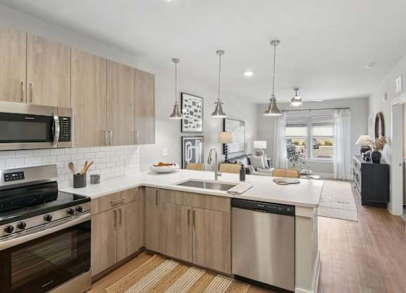 A modern kitchen with wooden cabinets and stainless steel appliances at The Hendry Apartments, Fort Myers