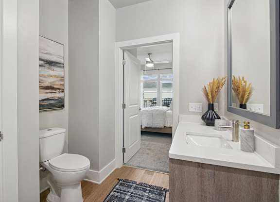 A bathroom with a toilet, sink, and mirror at The Hendry Apartments, Fort Myers, Florida