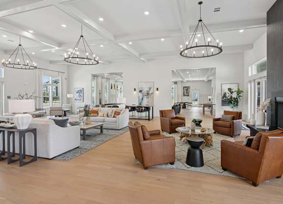 A spacious living room with brown leather chairs and a white sofa at The Hendry Apartments, Fort Myers, FL, 33905