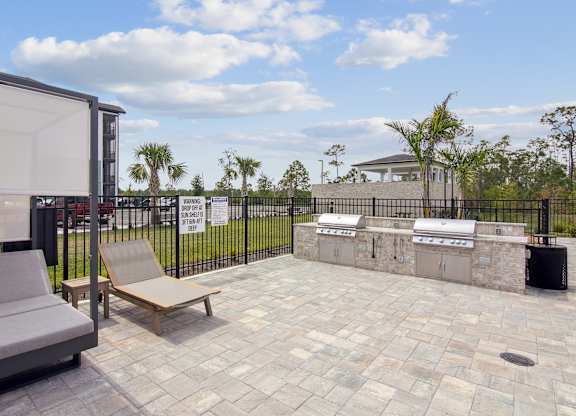 A patio with a grey sofa and a wooden bench at The Hendry Apartments, Fort Myers