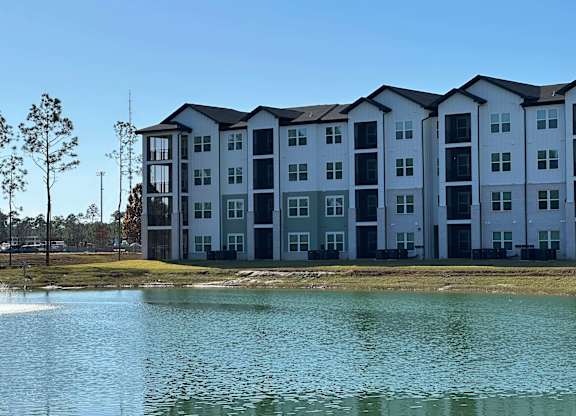 A large white building with a lake in front of it at The Beacon at 331 Apartments, Santa Rosa Beach