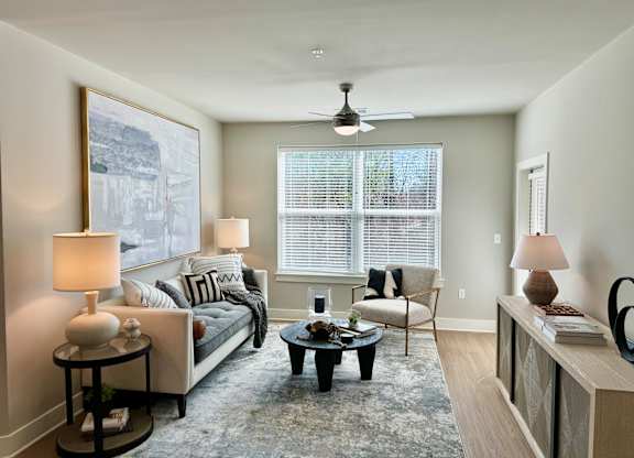 A living room with a couch, a chair, a coffee table, and a painting on the wall at The Collective Upper Westside Apartments, Atlanta, GA