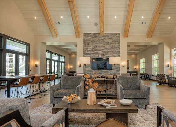 A living room with a stone fireplace and wooden beams at The Ashton at East Park Apartments, Kennesaw