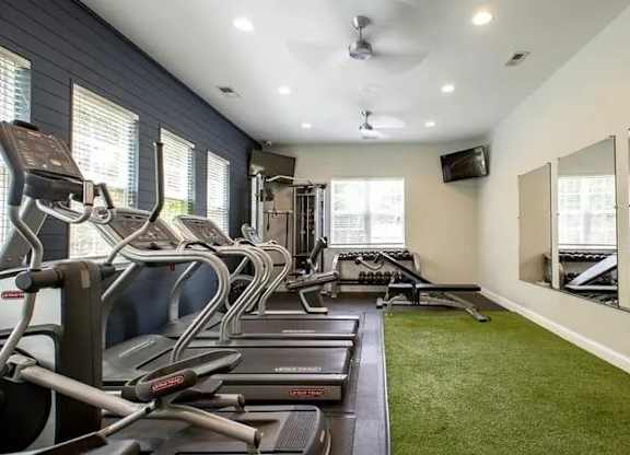 A gym with treadmills, exercise bikes, and mirrors.