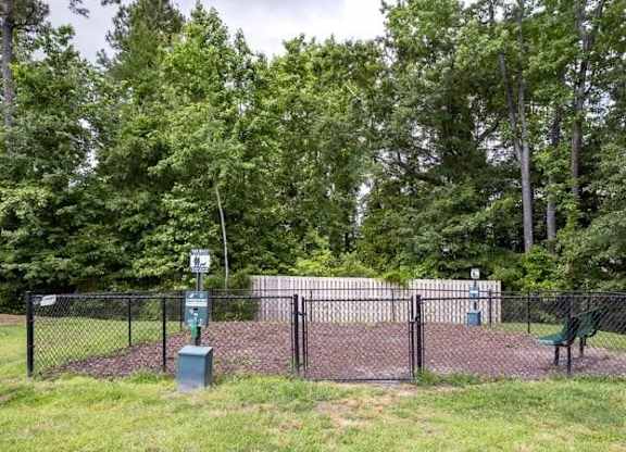A playground surrounded by a black fence with a green slide.