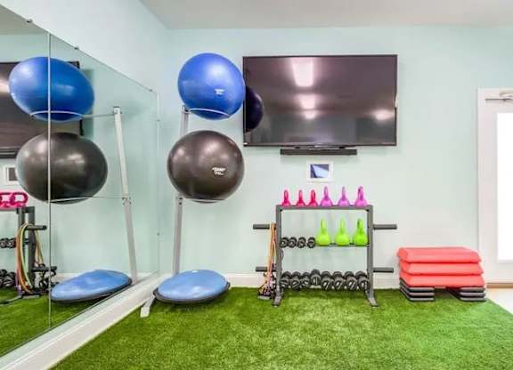 A gym room with a green carpet and exercise equipment.