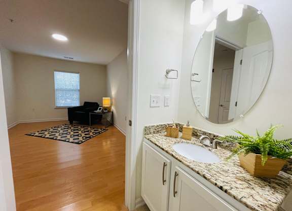 A bathroom with a sink, mirror, and wooden floors.