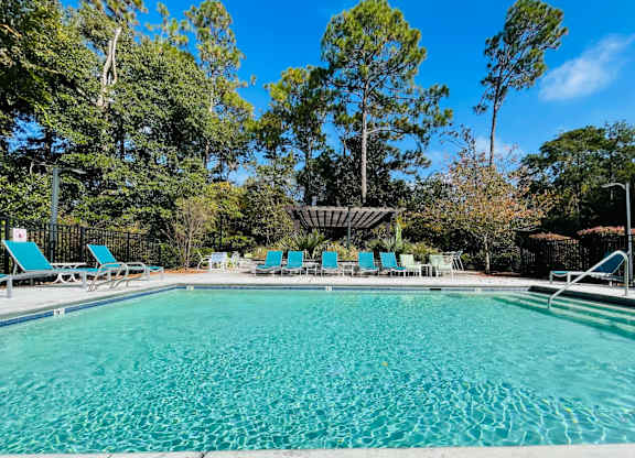 A large swimming pool surrounded by trees and lounge chairs.