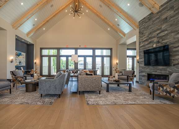 A living room with a stone fireplace and a large TV mounted on the wall at The Ashton at East Park Apartments, Kennesaw, GA, 30144