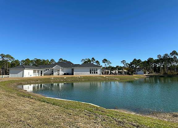 A large house with a pond in front of it at The Beacon at 331 Apartments, Santa Rosa Beach, FL, 32459