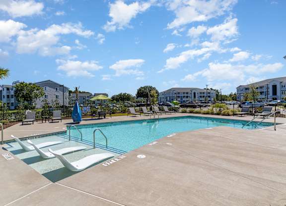 our resort style swimming pool is next to a row of apartment buildings