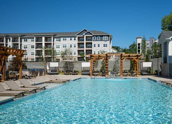 A large swimming pool with lounge chairs and a wooden pergola at The Ashton at East Park Apartments, Kennesaw, 30144