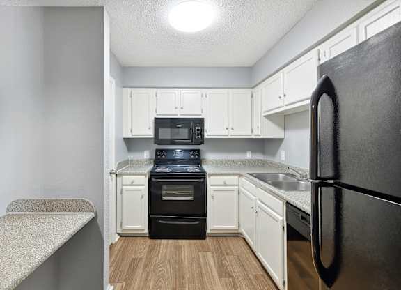 A kitchen with a black refrigerator and white cabinets  at Governors House, Huntsville, 35805