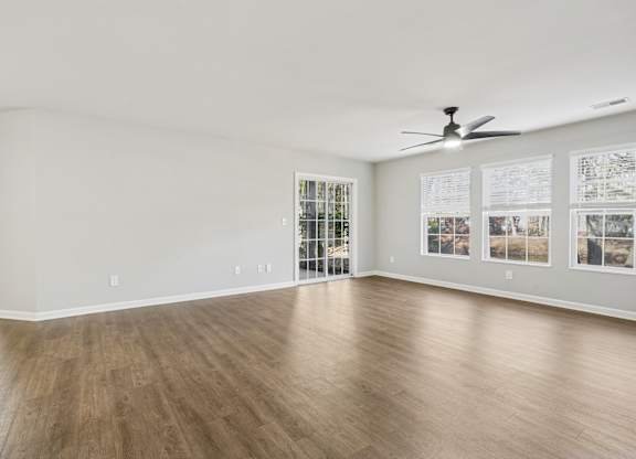 A spacious room with a ceiling fan and wood flooring.