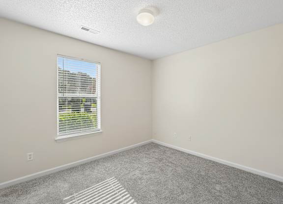 A room with a window and a striped rug on the floor.