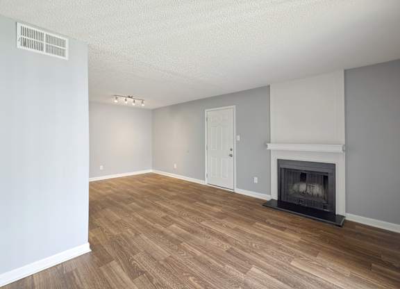 an empty living room with a fireplace and wooden floors  at Governors House, Alabama