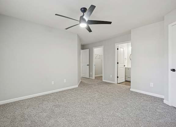 A room with a ceiling fan and carpeted floor.